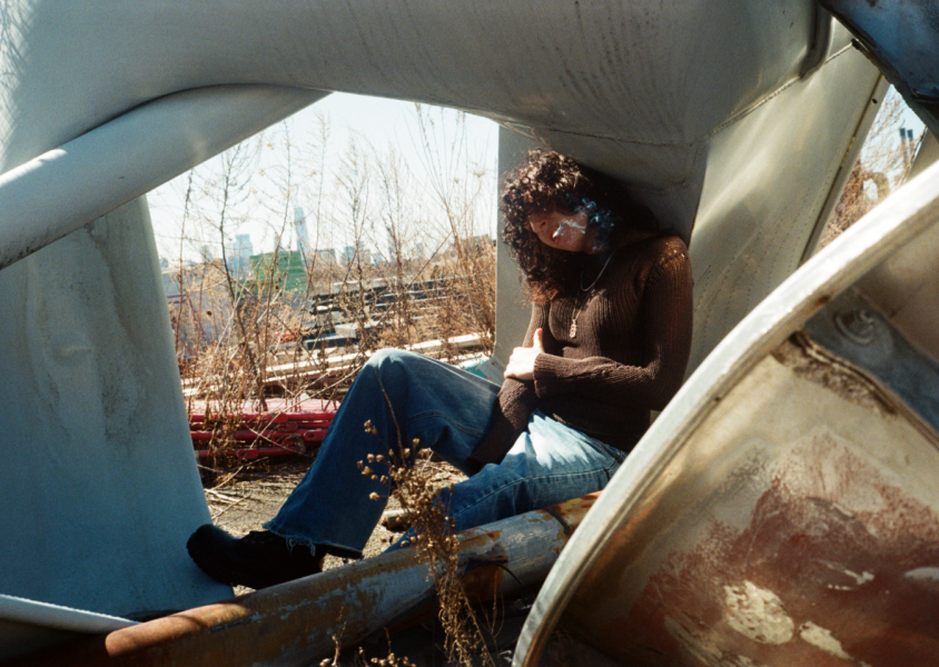 Artist Jane Remover sitting in a Junk Yard smoking a cigarettex
